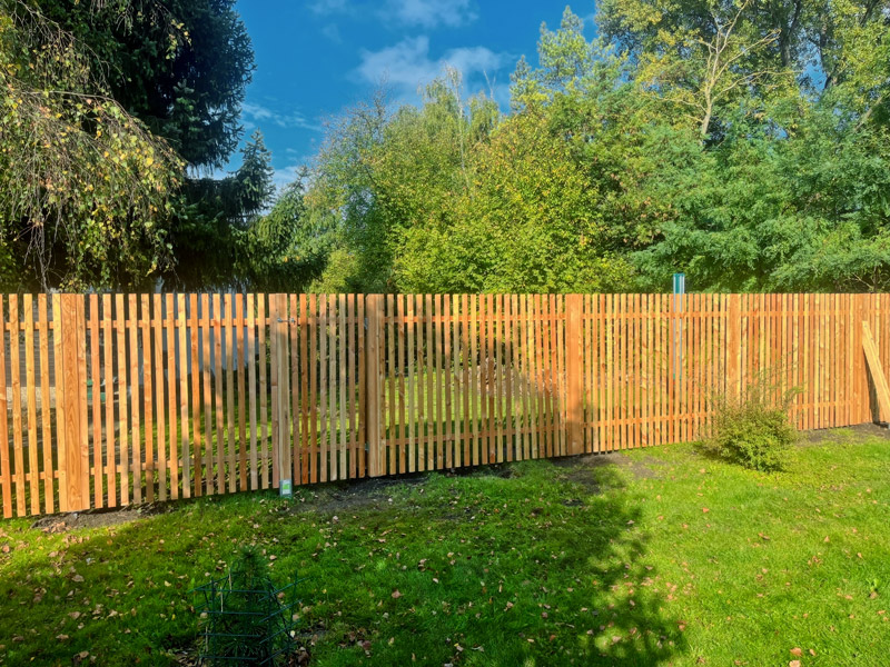 Holzzäune harmonieren mit dem grünen Garten und Bäumen auf natürliche Weise.